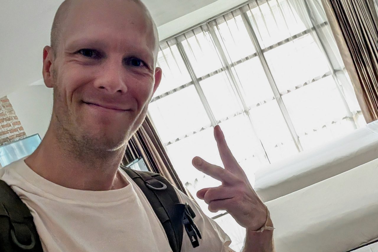 Nikolaj Mandsberg with a shaved head and a backpack, in a hotel room in Thailand, shortly after leaving the monastery.
